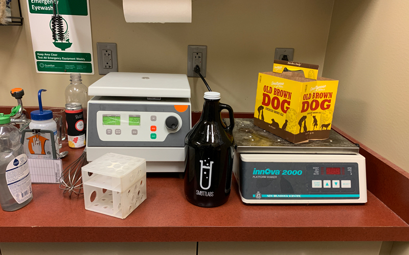 A big beer bottle sits on a lab bench next to lab equipment.