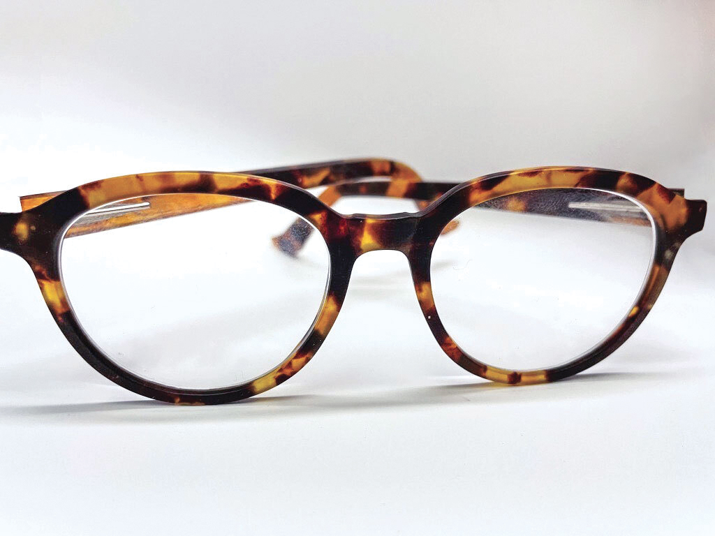 A pair of glasses made of mottled yellow, orange, and black plastic on a white background.