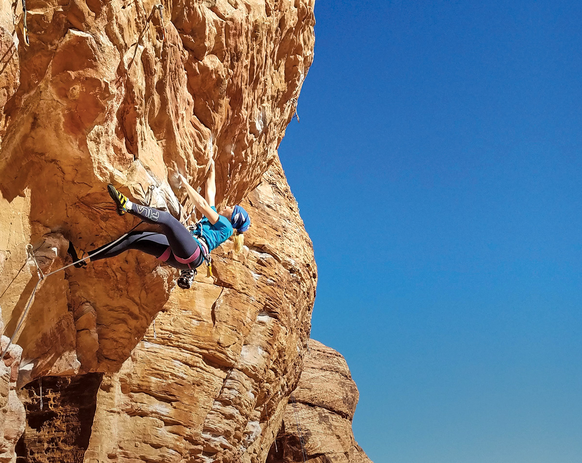 A rock climber ascends a vertical surface.