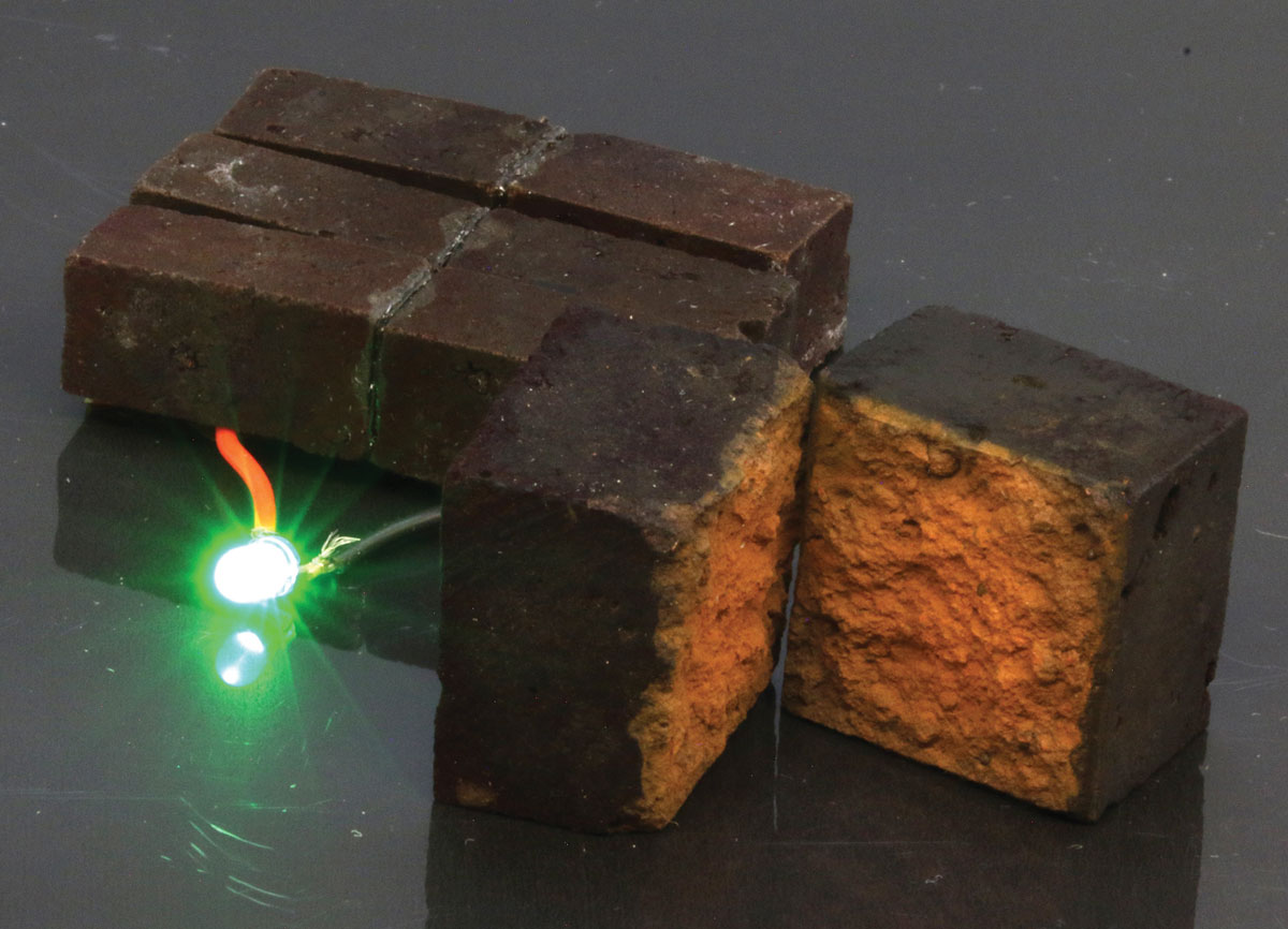 Photo of supercapacitor bricks connected to a glowing light-emitting diode.
