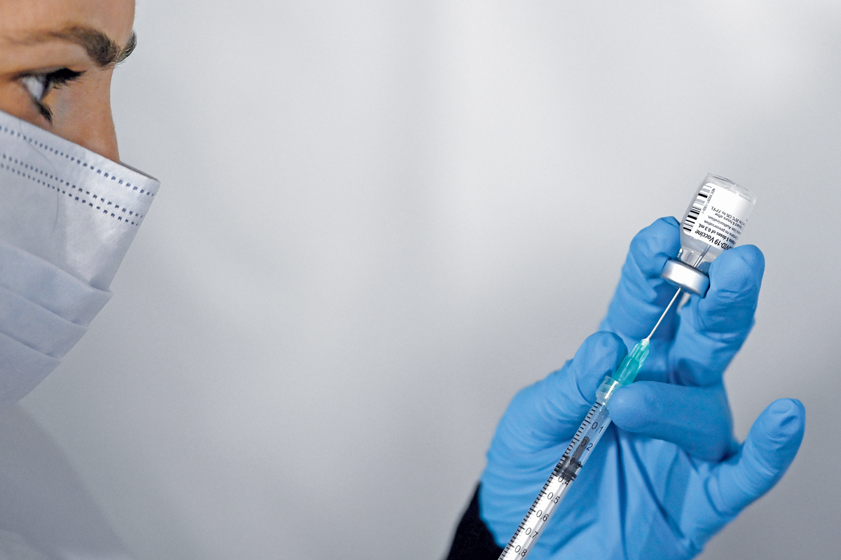 A masked medical worker preparing a shot of the Pfizer-BioNTech COVID-19 vaccine.