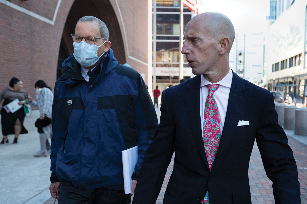 Charles Lieber, wearing a mask, walks alongside his lawyer Marc Mukasey